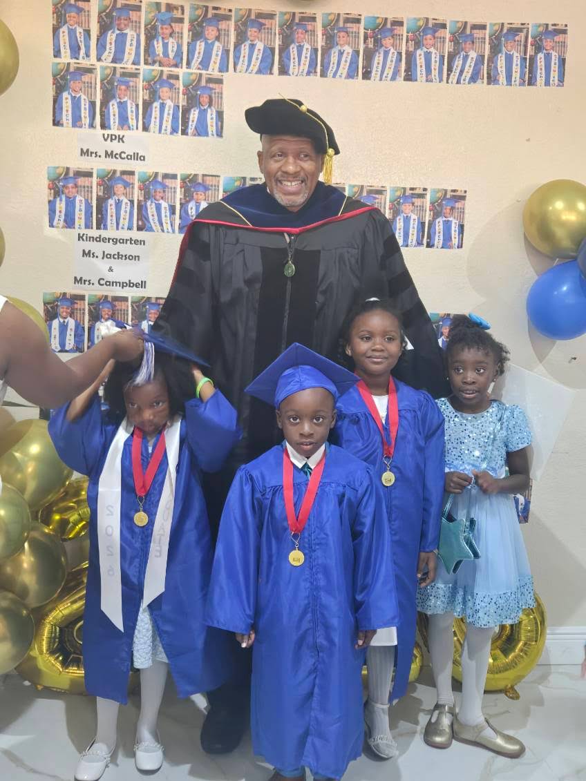Dr. Jennings in doctoral regalia celebrating young graduates in cap and gown